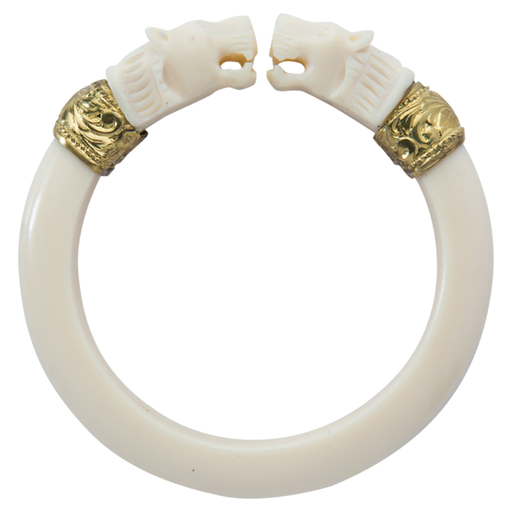 This double-headed roaring lion bangle is handmade of smooth ivory colored bakelite with repousee gold bands. Appears antique or vintage. Sewit Sium jewelry.